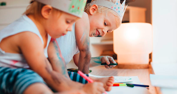 Zwei Kinder sitzen am Boden und malen mit Buntstiften während dem Babysitter Kurs in Graz