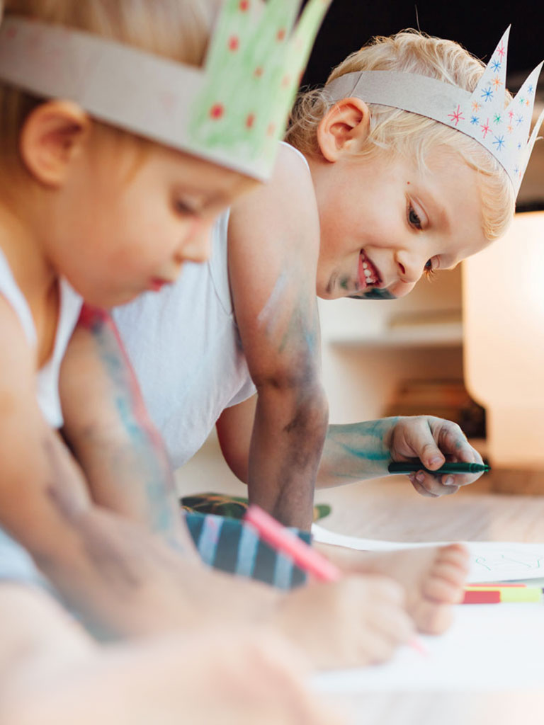 Zwei Kinder sitzen am Boden und malen mit Buntstiften während dem Babysitter Kurs in Graz