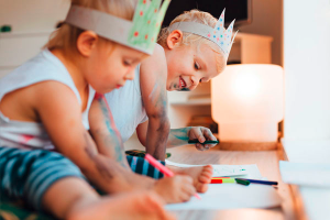 Zwei Kinder sitzen am Boden und malen mit Buntstiften während dem Babysitter Kurs der Babysitterei in Wien